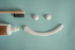 Toothpaste and toothbrush arranged with a smiley face made from toothpaste